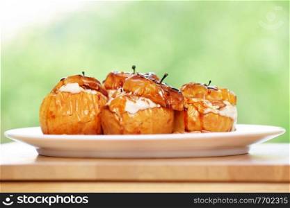 Closeup photo of a tasty baked apples stuffed with cheese cream, flavored with cinnamon, nuts and honey, served on the white plate, healthy nutrition, delicious fruit dessert