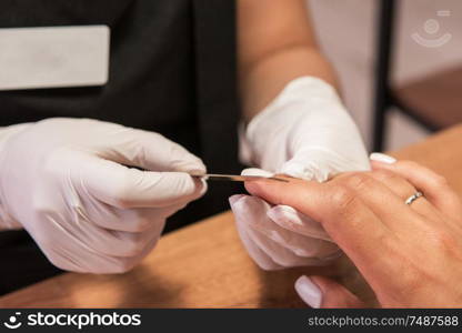 Closeup photo of a woman in a nail salon receiving a manicure by a beautician with nail file.. Woman in a nail salon