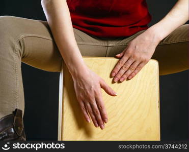 Closeup photo of a woman playing a Cajon percussion instrument.