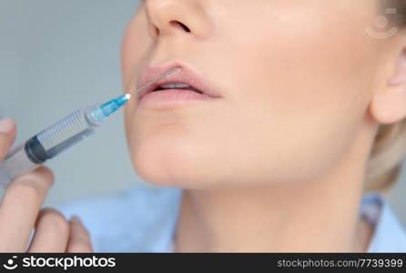 Closeup Photo of a Women&rsquo;s Face Part with Syringe over Gray Background. Lip Augmentation Procedure. Nice Female in a Beauty Clinic.. Lip Augmentation in The Clinic