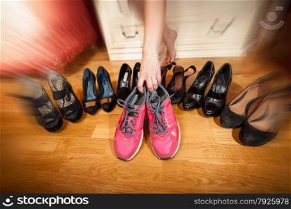 Closeup photo of active woman picking sneakers rather than high heels. Photo with motion blur