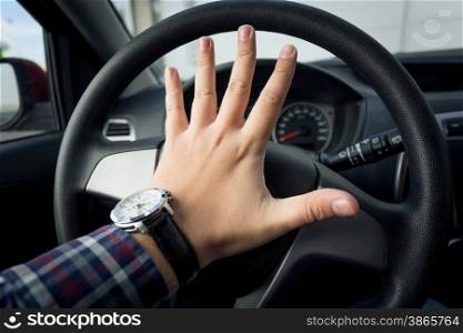 Closeup photo of angry driver honking in traffic
