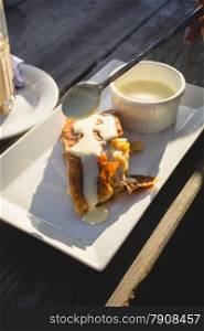 Closeup photo of apple strudel with vanilla sauce on wooden table