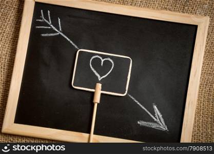 Closeup photo of arrow going through heart drawn on blackboard