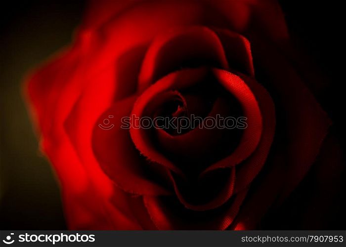 Closeup photo of artificial red rose shot against black background