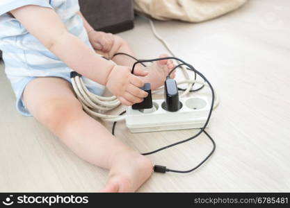 Closeup photo of baby boy pulling out cables from electrical extension