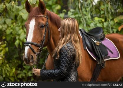 Closeup photo of beautiful woman holding horse by rein