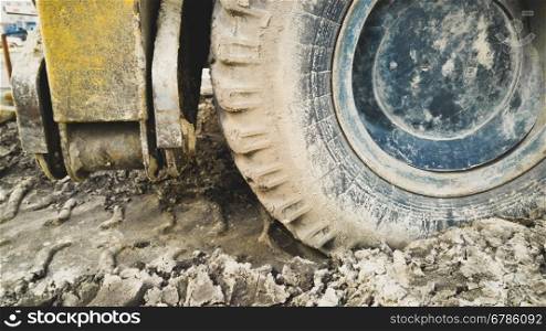 Closeup photo of big excavator wheels covered with mud