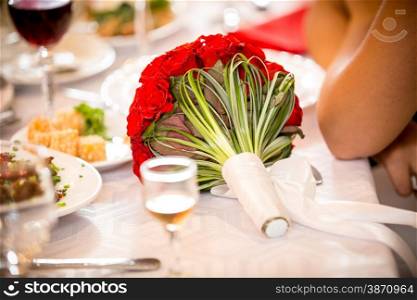Closeup photo of big red bouquet lying on table at restaurant