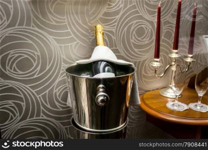 Closeup photo of bottle of champagne standing in bucket at restaurant