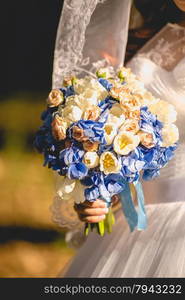 Closeup photo of bride holding wedding bouquet in hand