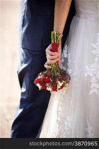Closeup photo of bride hugging groom and holding wedding bouquet