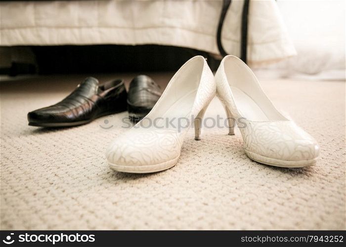 Closeup photo of brides and grooms shoes on floor at bedroom
