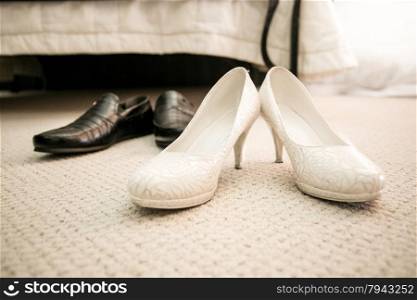 Closeup photo of brides and grooms shoes on floor at bedroom