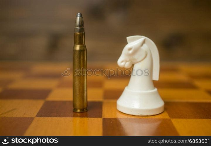 Closeup photo of bullet standing on chessboard with another chess piece