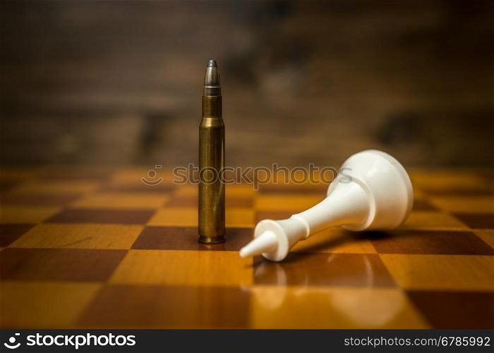 Closeup photo of bullet wins chess game. Concept of gun power