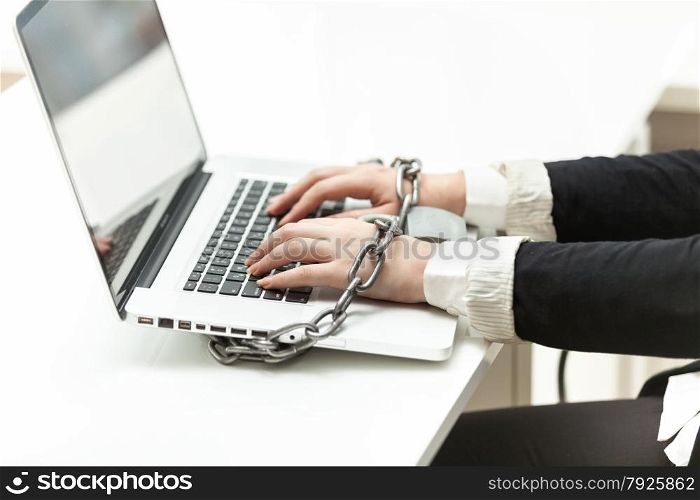 Closeup photo of businesswoman locked to laptop by chain