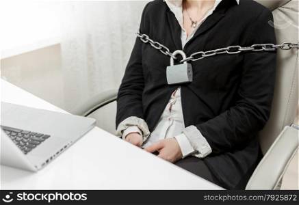 Closeup photo of businesswoman tied to chair by metal chain