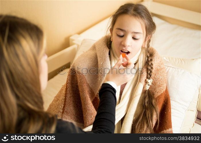 Closeup photo of caring mother giving sick daughter pills