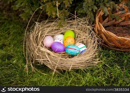 Closeup photo of colored Easter eggs lying in basket on yard