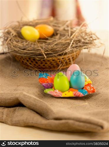 Closeup photo of colorful Easter eggs lying on table covered with burlap