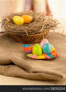 Closeup photo of colorful Easter eggs lying on table covered with burlap