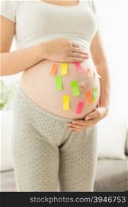 Closeup photo of colorful stickers on pregnant woman tummy