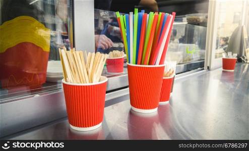 Closeup photo of cups, drinking straws and spoons on food truck counter