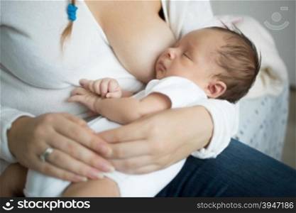 Closeup photo of cute baby sleeping on mothers hands after eating milk