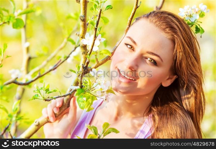 Closeup photo of cute female enjoying spring nature, blooming tree, relaxation outdoors, vacation concept