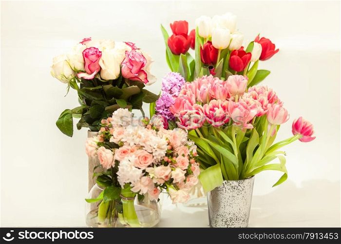 Closeup photo of different fresh cut flowers in vases against white background