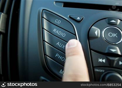 Closeup photo of driver pushing radio button on dashboard