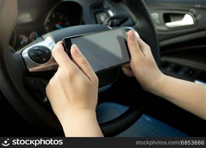 Closeup photo of driver typing message while driving a car