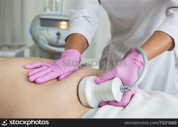 Closeup photo of fat man with big belly having cavitation procedure removing cellulite on abdomen in modern beauty clinic. Belly cavitation at modern beauty clinic
