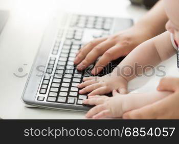 Closeup photo of father teaching his baby how to use computer keyboard