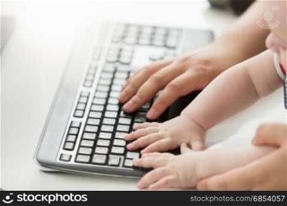 Closeup photo of father teaching his baby how to use computer keyboard