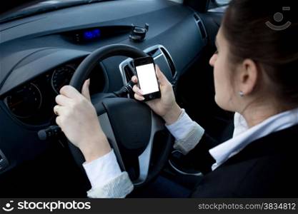 Closeup photo of female driver using smartphone while driving a car