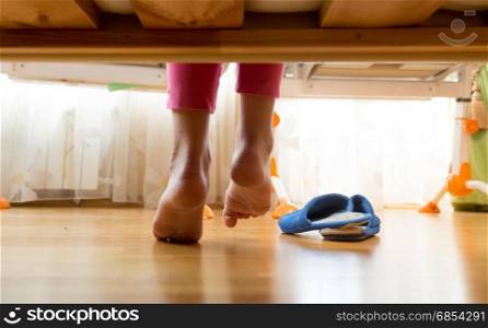 Closeup photo of female feet under the bed