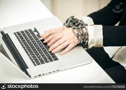 Closeup photo of female hand chained up to laptop