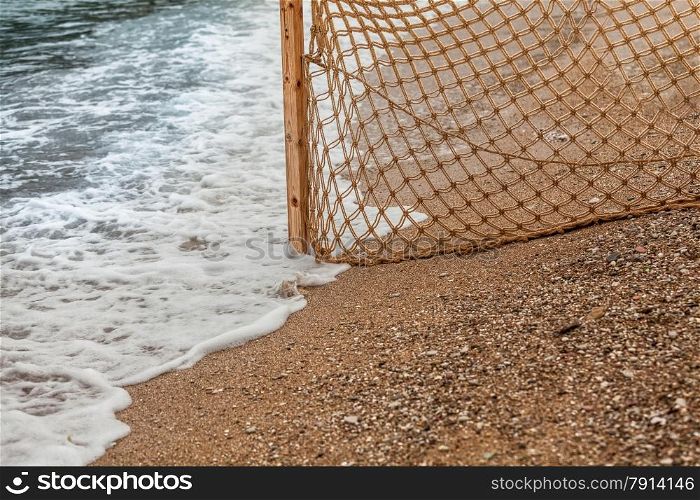 Closeup photo of fishing net on sandy beach at sea waves