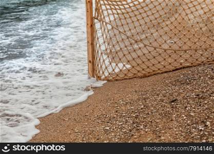Closeup photo of fishing net on sandy beach at sea waves