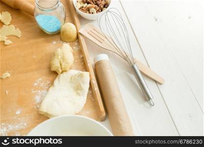 Closeup photo of fresh dough lying on wooden desk next to utensils