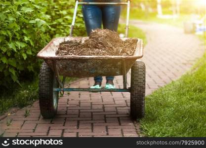 Closeup photo of garden wheelbarrow with earth at sunny day