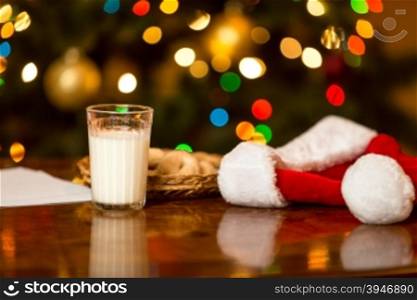 Closeup photo of glass of milk and cookies for Santa on table