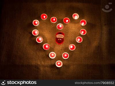 Closeup photo of golden ring in box lying in middle of heart shape of candles