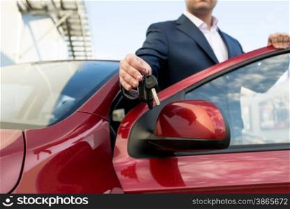 Closeup photo of handsome car salesman giving keys