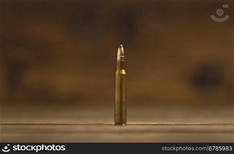 Closeup photo of Kalashikov riffle bullet on old wooden desk