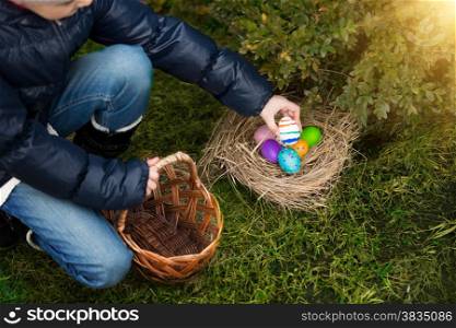 Closeup photo of little girl putting painted egg in basket