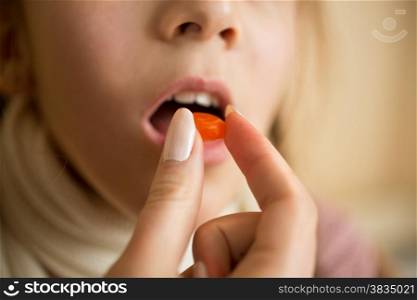 Closeup photo of little girl taking medicine in pill
