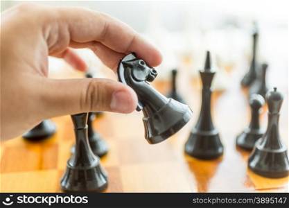 Closeup photo of male hand holding black horse chess piece